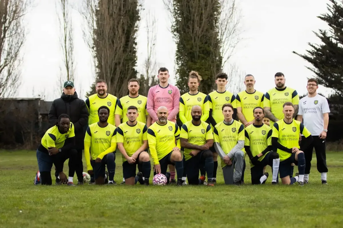 The Sue's Angels FC squad in the matchday kit, with the kit sponsor's name across the front of every shirt